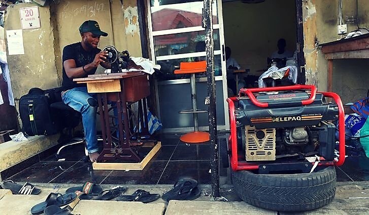 Nigerian man sitting on sewing machine